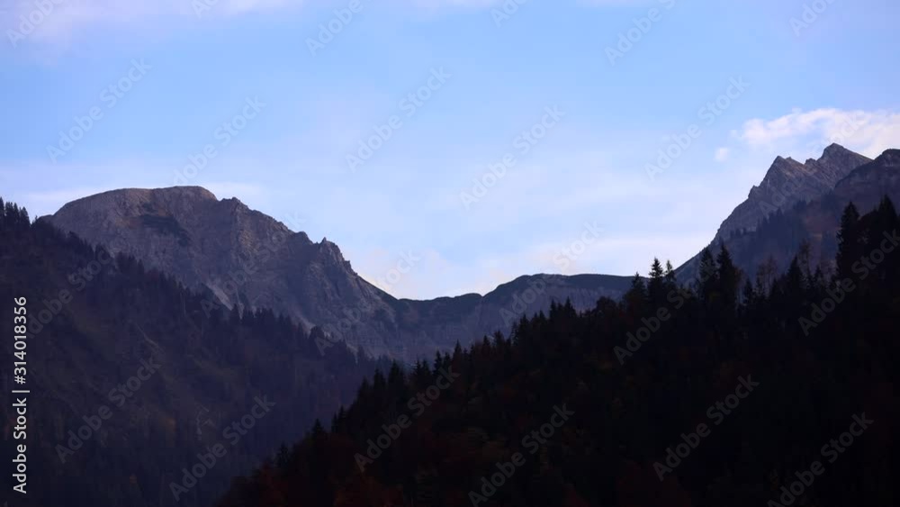 Puffy white clouds float past rugged looking ancient mountains in a fantasy-like timelapse scene Puffy white clouds float past rugged looking ancient mountains in a fantasy-like timelapse scene