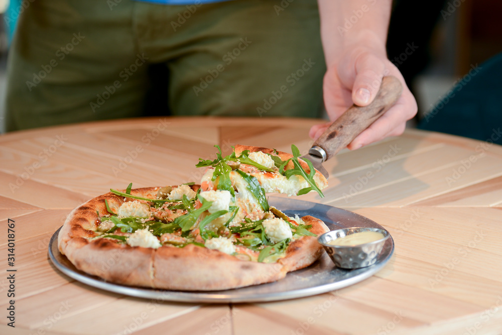 Delicious Italian large pizza served on a light wooden table in a restaurant. Restaurant food photography