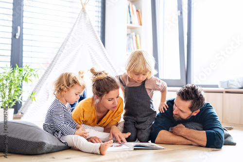Young family with two small children indoors in bedroom reading a book. photo