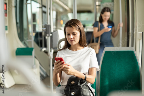 Woman using mobile phone in the cabin of a bus or tram