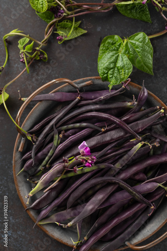 Fresh purple string beans on a black table, clean eating, selective focus. Top view.