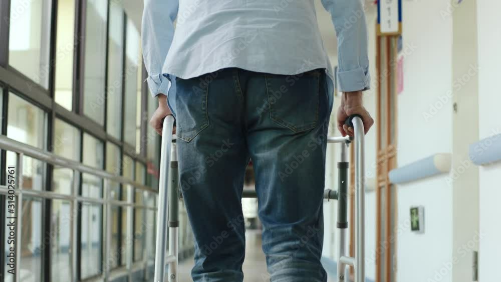 rear view of asian senior man walking using walker in hallway of nursing home or hospital rear view of asian senior man walking using walker in hallway of nursing home or hospital