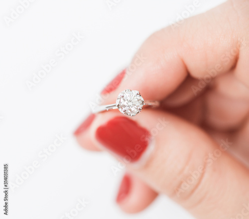 Close up of an elegant engagement diamond ring hold by women.