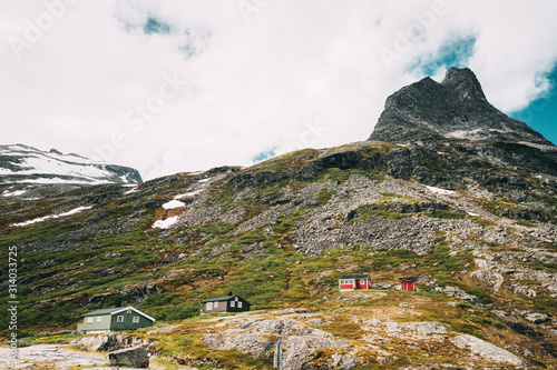 Trollstigen, Andalsnes, Norway. Wooden Houses In Mountains Landscape Near Road Trollstigen. Norwegian Landmark And Popular Destination. Norwegian County Road 63 In Sunny Summer Day photo