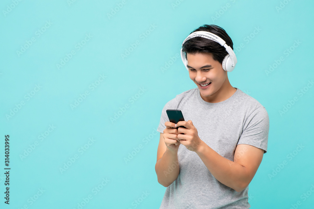Φωτογραφία Happy Asian man wearing wireless headphones listening to music from smartphone