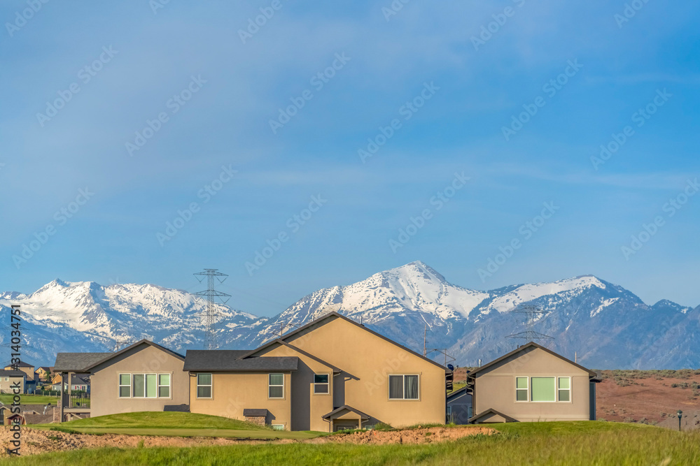Exterior of homes with power lines snow capped mountain and blue sky background