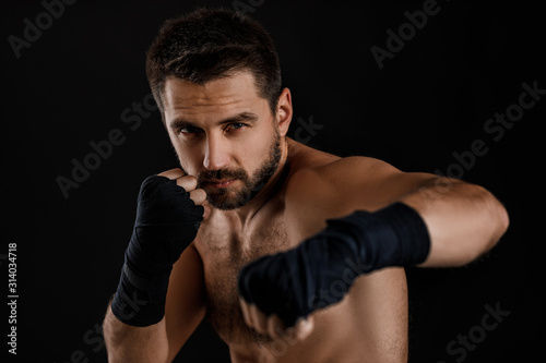 boxer man with bandage on hands training before fight and showing the different movements on black background © producer