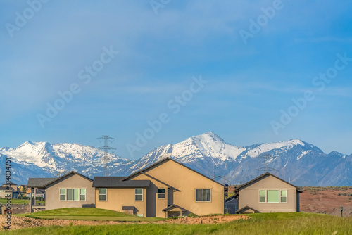 Exterior of homes with power lines snow capped mountain and blue sky background © Jason