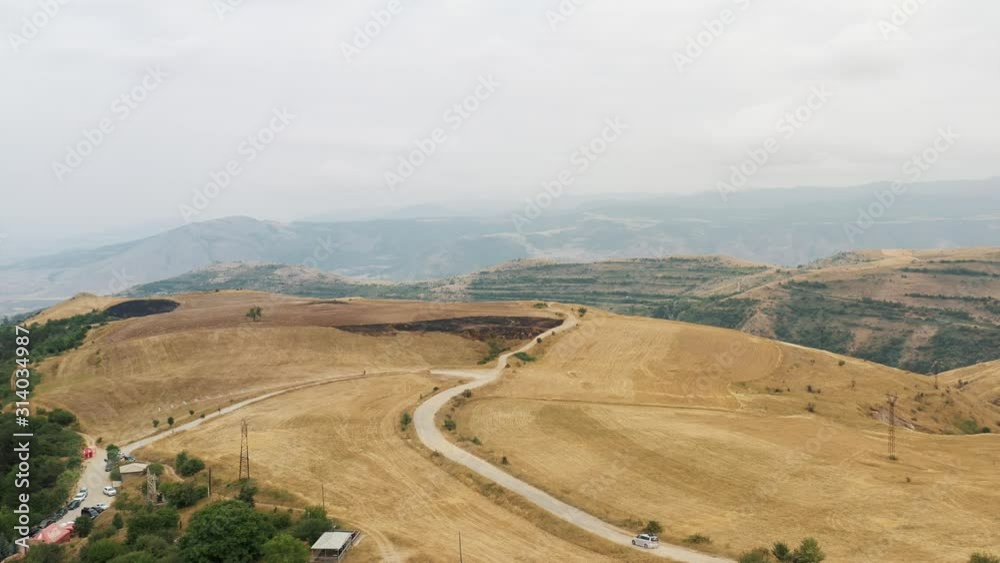 Aerial drone zoom in of hills, houses by the cliff and road on background of mountains in Armenia, armenian beautiful landscape in summer Aerial drone zoom in of hills, houses by the cliff and road on background of mountains in Armenia, armenian beautiful landscape in summer