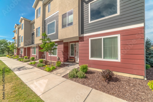 Townhomes exterior with red gray and beige wall against blue sky on a sunny day