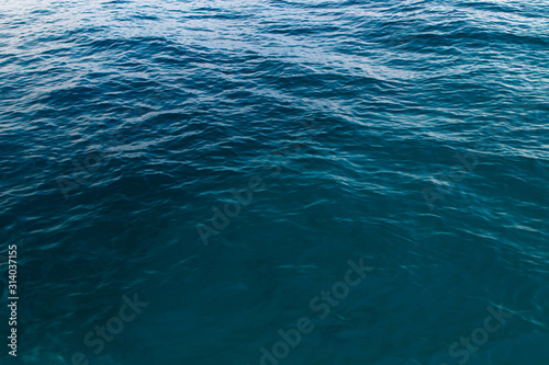 Clear water texture in blue. Background of the ocean and the sea backlit by the sun. © Alwih