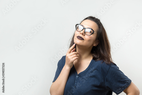 Image of excited young lady with glasses. Looking camera have an idea. Stands on a white background.