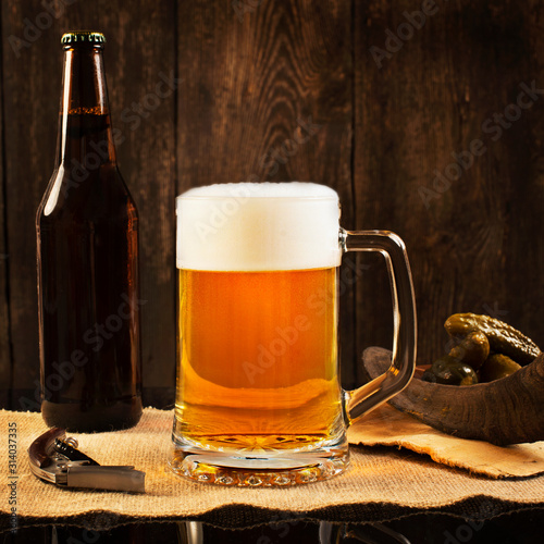 Pint of beer with bottle on rustic wooden background
