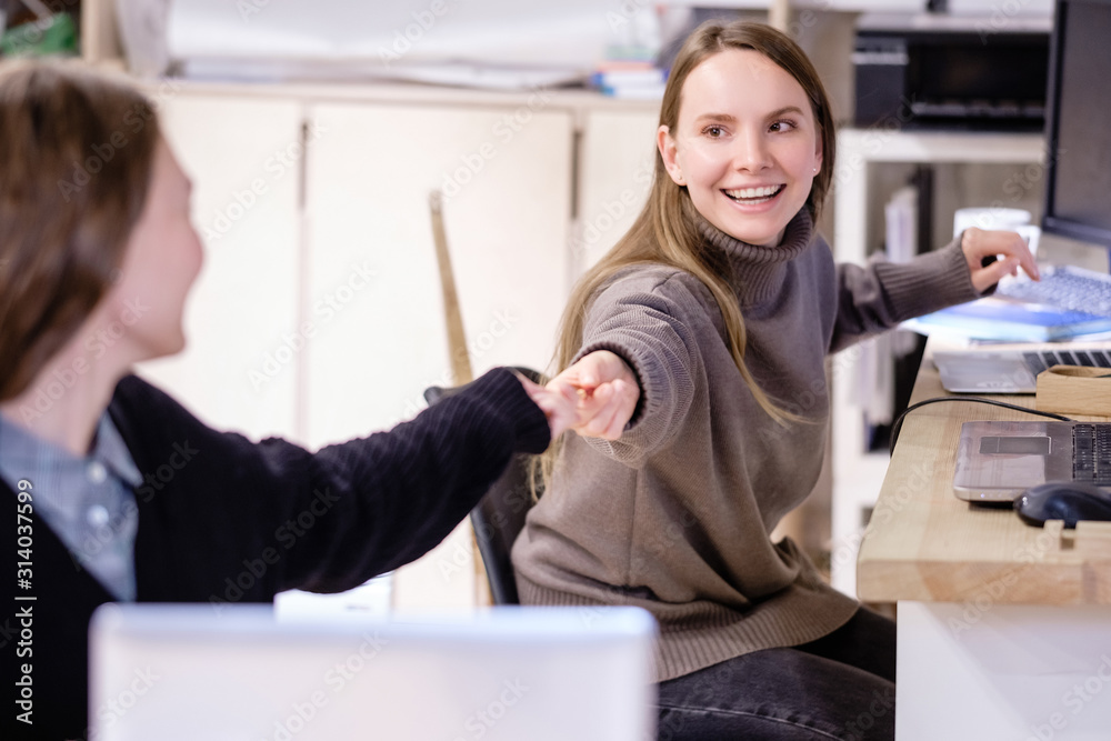 Φωτογραφία Two successful beautiful caucasian positive young women employees of a large company pass each other a pen