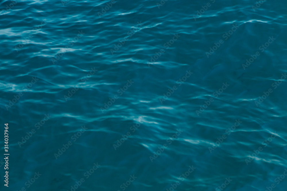 Obraz premium Clear water texture in blue. Background of the ocean and the sea backlit by the sun.
