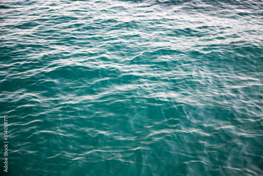 Clear water texture in blue. Background of the ocean and the sea backlit by the sun. Clear water texture in blue. Background of the ocean and the sea backlit by the sun.