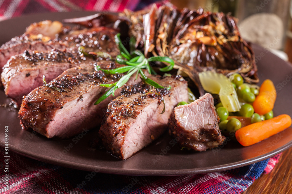 Slices of beef steak served with baked artichoke