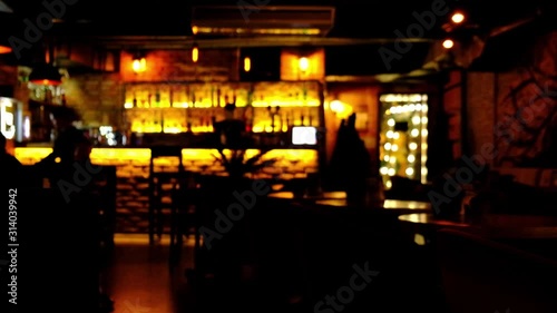 Blurred video of the interior of a large beautiful restaurant in low lighting. The waitress comes to the table and gives the visitors a menu and goes for drinks. Defocused restaurant