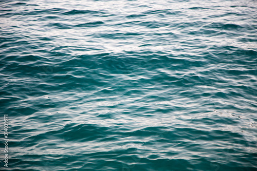 Clear water texture in blue. Background of the ocean and the sea backlit by the sun.