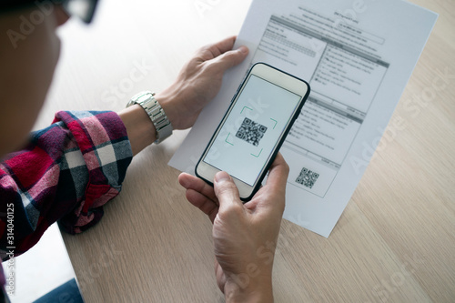Photography A man uses a smartphone to scan the QR code to pay monthly credit card bills after receiving an invoice sent to home