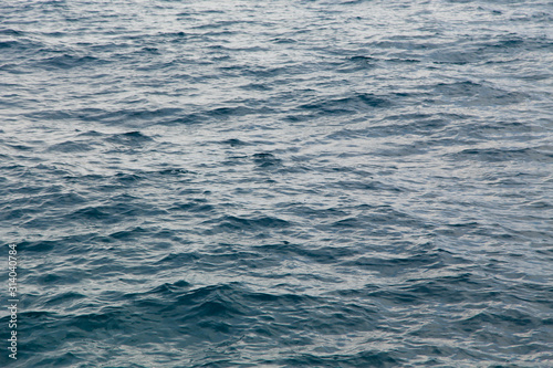 Clear water texture in blue. Background of the ocean and the sea backlit by the sun.