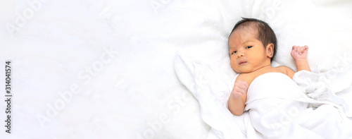 Cute newborn baby girl in white blanket on nursery bed. Adorable new born child, little boy eyes look people Family, new childhood, infant soft skin portrait concept. Jaundice syndrome life hospital.