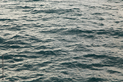 Clear water texture in blue. Background of the ocean and the sea backlit by the sun. © Alwih