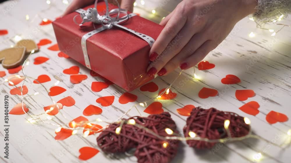 Female hands put a gift box on the desk, close up. Valentine's day concept. Female hands put a gift box on the desk, close up. Valentine's day concept.