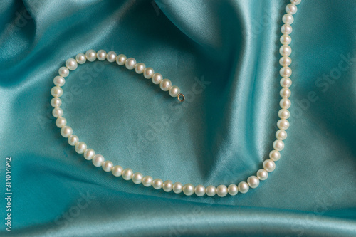 elegant fashion and bridal gift concept. Luxury pearl necklace on blue silk background, holiday glamour jewelery present