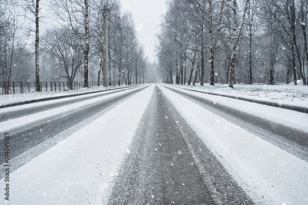 Winter country road in snowfall. Wheel tracks on a snowy road Winter country road in snowfall. Wheel tracks on a snowy road