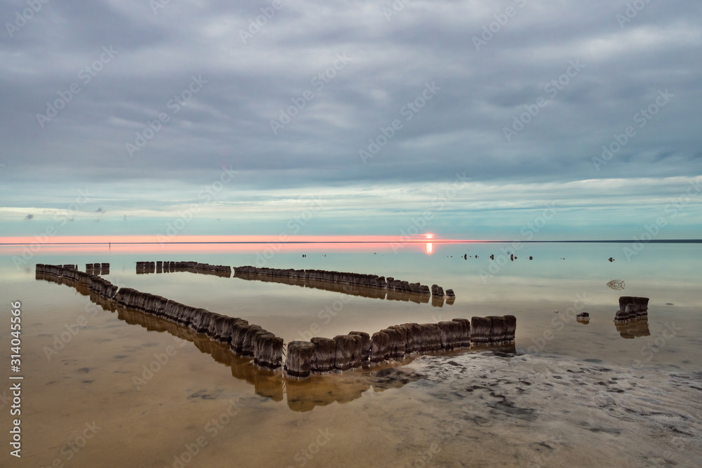 Old wooden pool in front of Sunset clouds reflected in the smooth water of the salt lake
