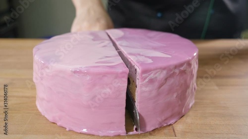 Cutting cake into two parts on wooden table. Close-up shot of sharp knife cutting cake in slow motion. Confectioner at Bakery serving dessert .Fudgie the Whale. Full hd photo