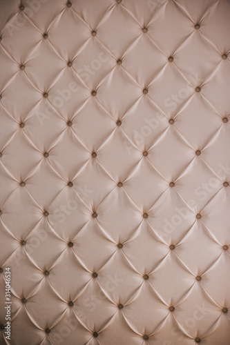 Wall with white leather upholstery. Relief wall. Furniture texture