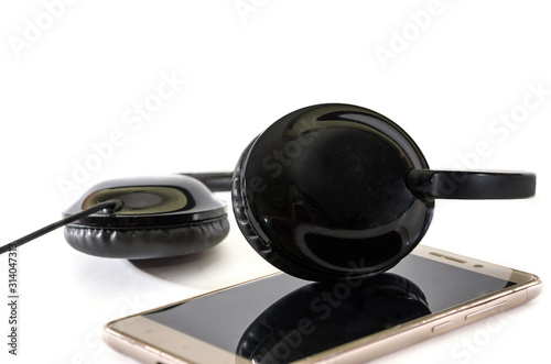 black headphones and smartphone on a white background. Close-up.