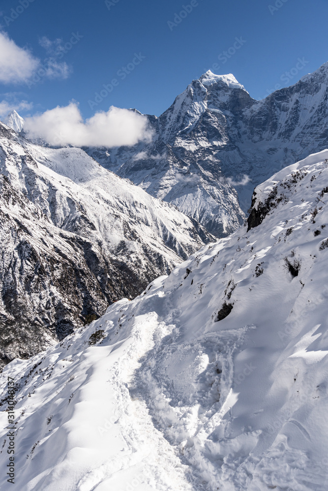 Snow covered hiking trail in the Himalaya with the Kangtega peak in the distance in the Gokyo valley in Nepal