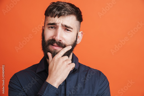 Image of serious man with nose jewelry thinking and touching his chin