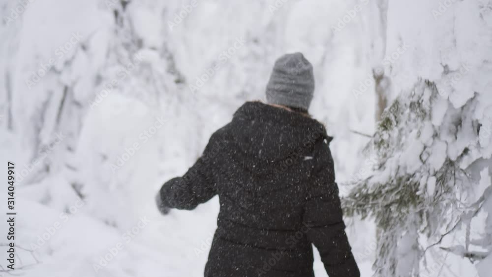 Girl is walking in winter snowy forest, turning back and throwing snow and smiling to camera. Winter funs concept. Asian model with happy cheerful emotions. Slow motion. Girl is walking in winter snowy forest, turning back and throwing snow and smiling to camera. Winter funs concept. Asian model with happy cheerful emotions. Slow motion.