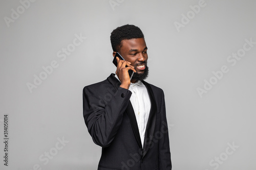 Cheerful businessman talking on mobile phone isolated on gray background
