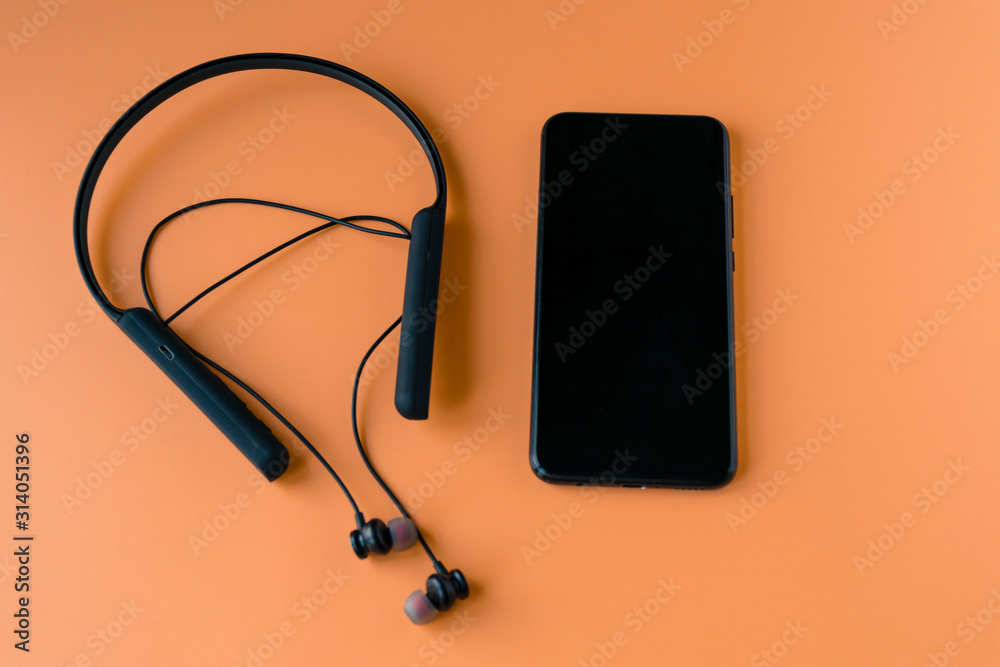 Black wireless bluetooth headphones for the phone on an orange background. Headset for the phone.. Black wireless bluetooth headphones for the phone on an orange background. Headset for the phone..