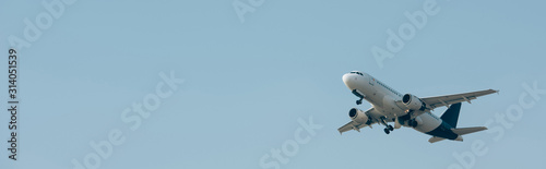 Panoramic shot of jet plane taking off in blue sky with copy space
