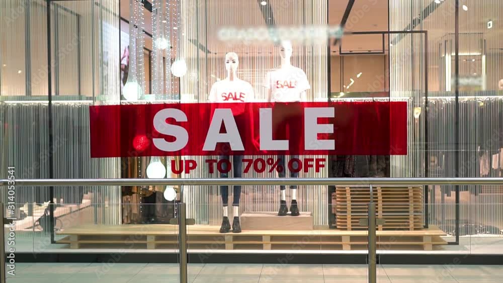 A huge inscription Sale on a red background on the entire window of a fashion boutique shop on the street in the center. The concept of buying and selling.
