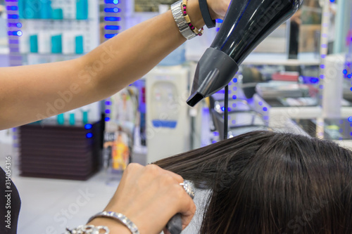 Peluquera peinando el cabello de su clienta en su negocio