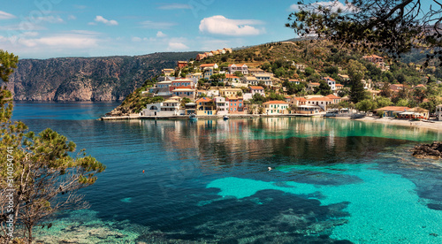 Wonderful Sunny seascape of Asos village, Kefalonia Island. Greece. Sunny spring seascape. Incredible buht with clear water of Ionian Sea. Beautiful landscape with bay on colorful buildings