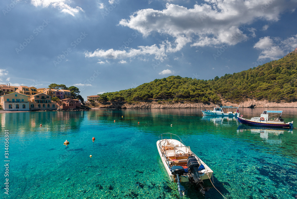 Wonderful Sunny seascape. boats  in beautiful turquoise ocean near an island. Amazing Coastline with Colorful Houses under sunlight.Wonderful morning seascape of Ionian Sea. Assos. Kefalonia. Greece