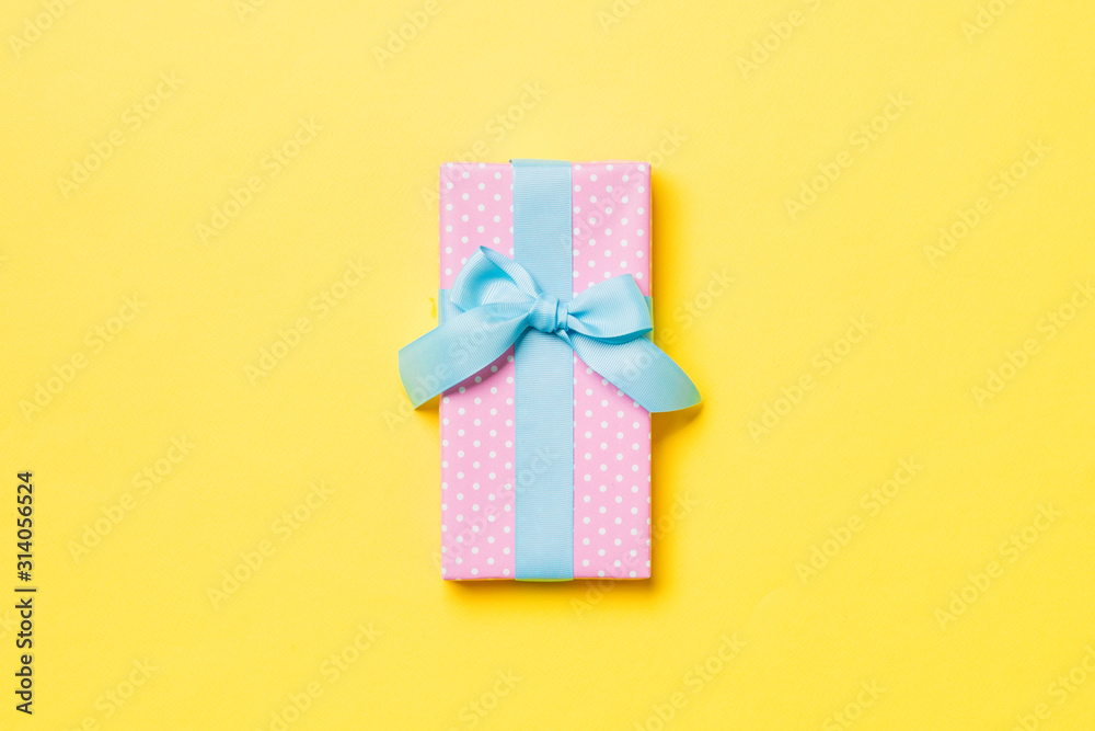Top view Christmas present box with blue bow on yellow background with copy space Top view Christmas present box with blue bow on yellow background with copy space
