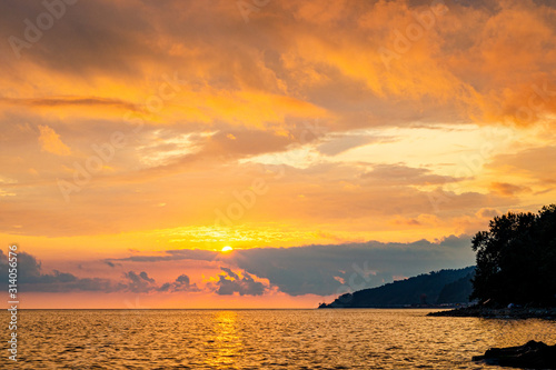 Dramatic orange sky at sunset. Clouds. Island in the sea