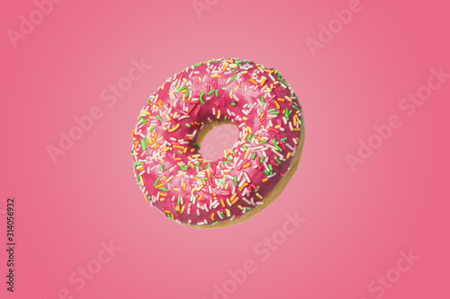 Donut with icing and sugar sprinkles on a pink background.