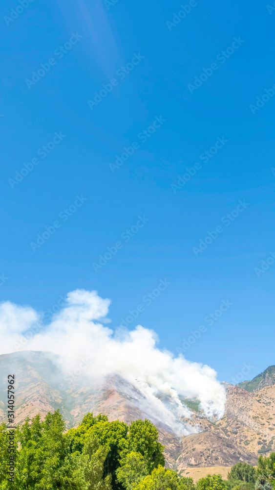 Vertical frame Scenic nature view on a sunny day with smoke from fire in the mountains
