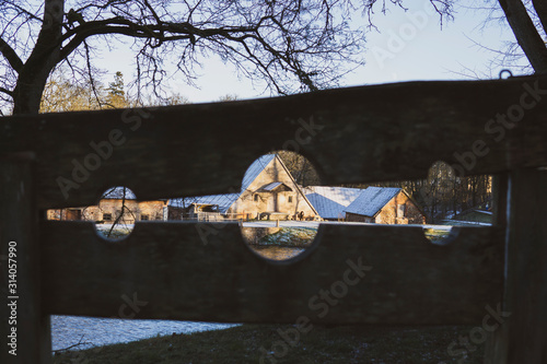 View through old  guillotine's hole to old houses under snow on the riverside. Magnificent landscape in cold sunny day. Jaunpils, Latvia. photo