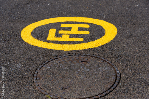 South Africa. December 2019. A freshly painted fire hydrant yellow sign alongside a manhole cover. © petert2